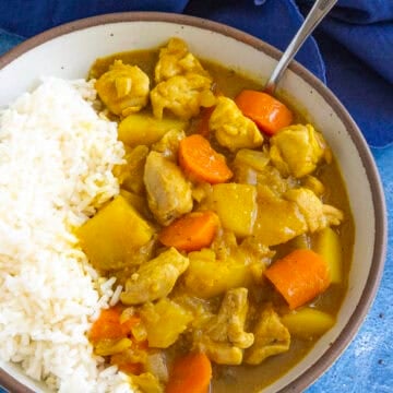 A bowl filled with hearty Japanese style curry with lots of potatoes and carrots, served with rice
