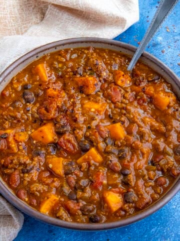A large bowl of spicy pumpkin chili, loaded with chunks of pumpkin, ground beef, and 2 types of beans