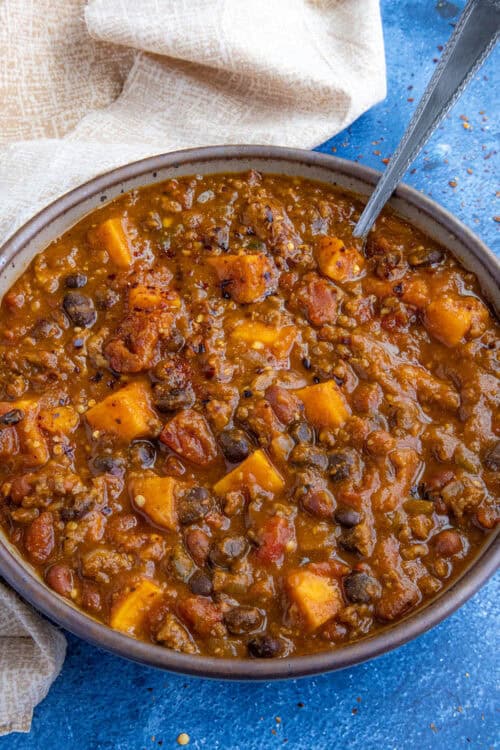 A large bowl of spicy pumpkin chili, loaded with chunks of pumpkin, ground beef, and 2 types of beans