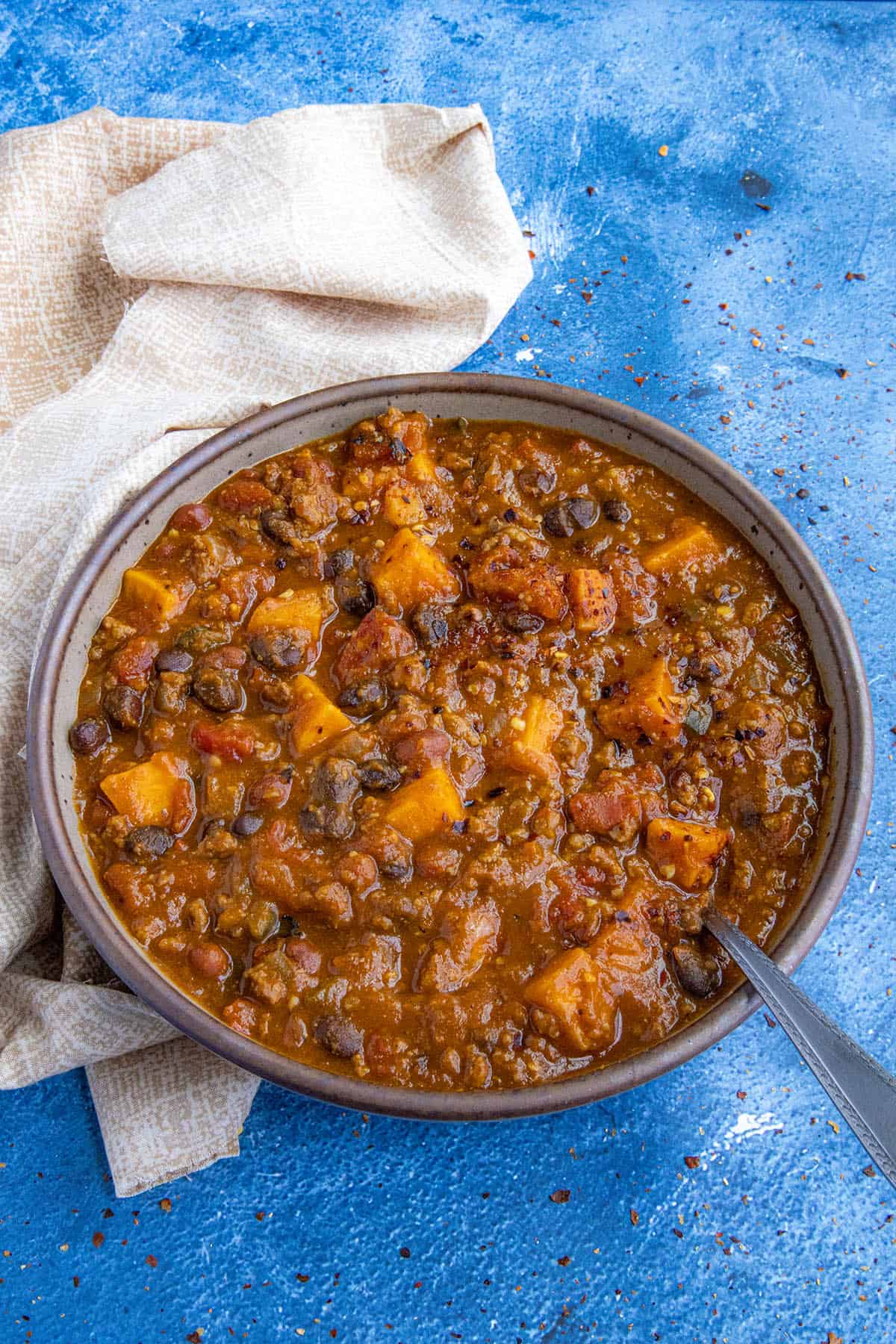 A bowl full of hearty pumpkin chili with lots of pumpkin, ground beef, and beans