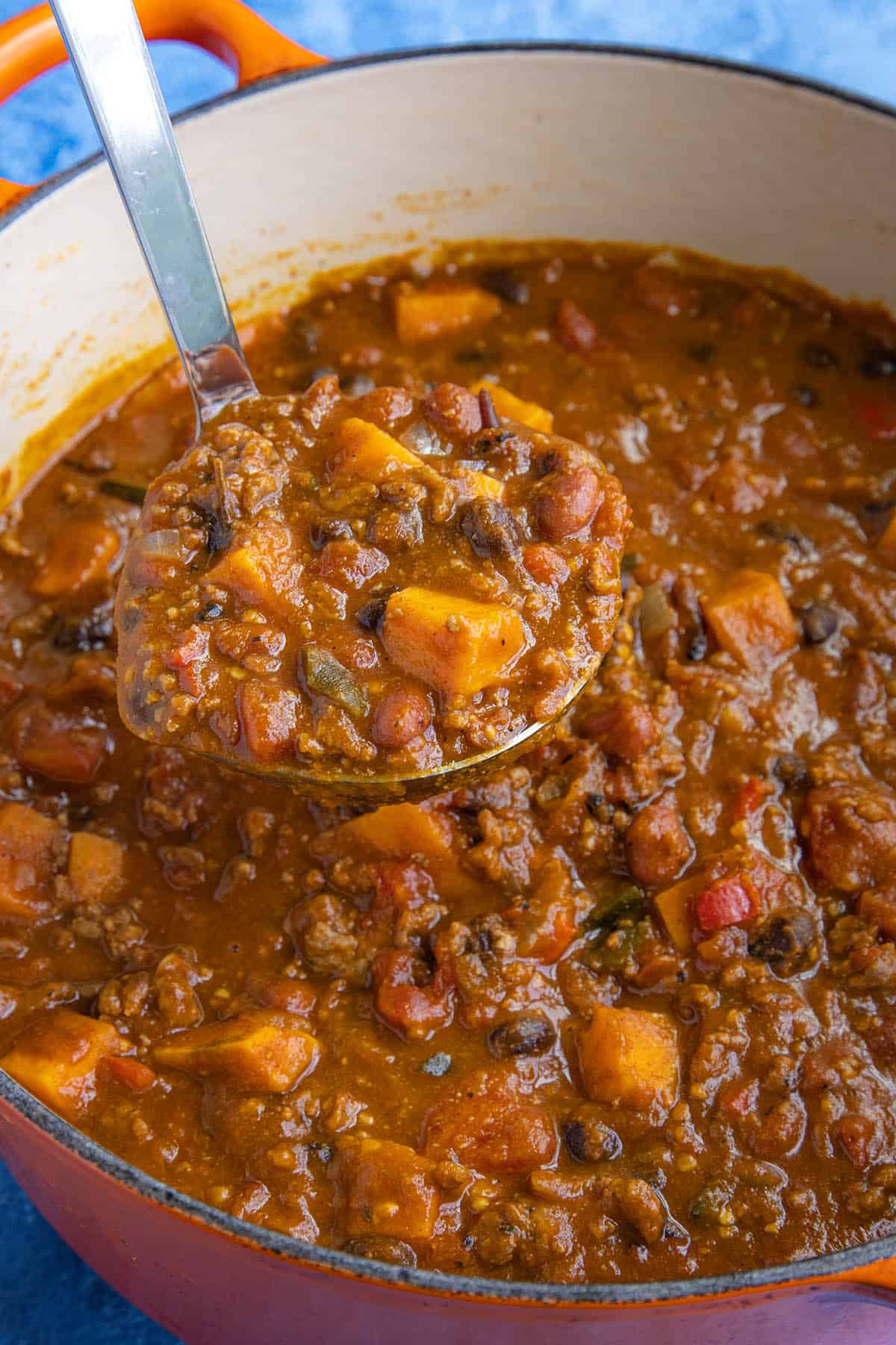 Mike lifting a large scoop of pumpkin chili from the pot