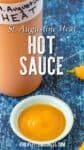 A bottle of St. Augustine Heat Hot Sauce alongside a small bowl of the hot sauce