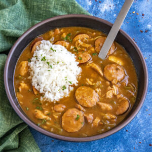 Cajun Chicken and Sausage Gumbo in a large bowl, topped with a generous scoop of white rice, garnished with fresh chopped parsley
