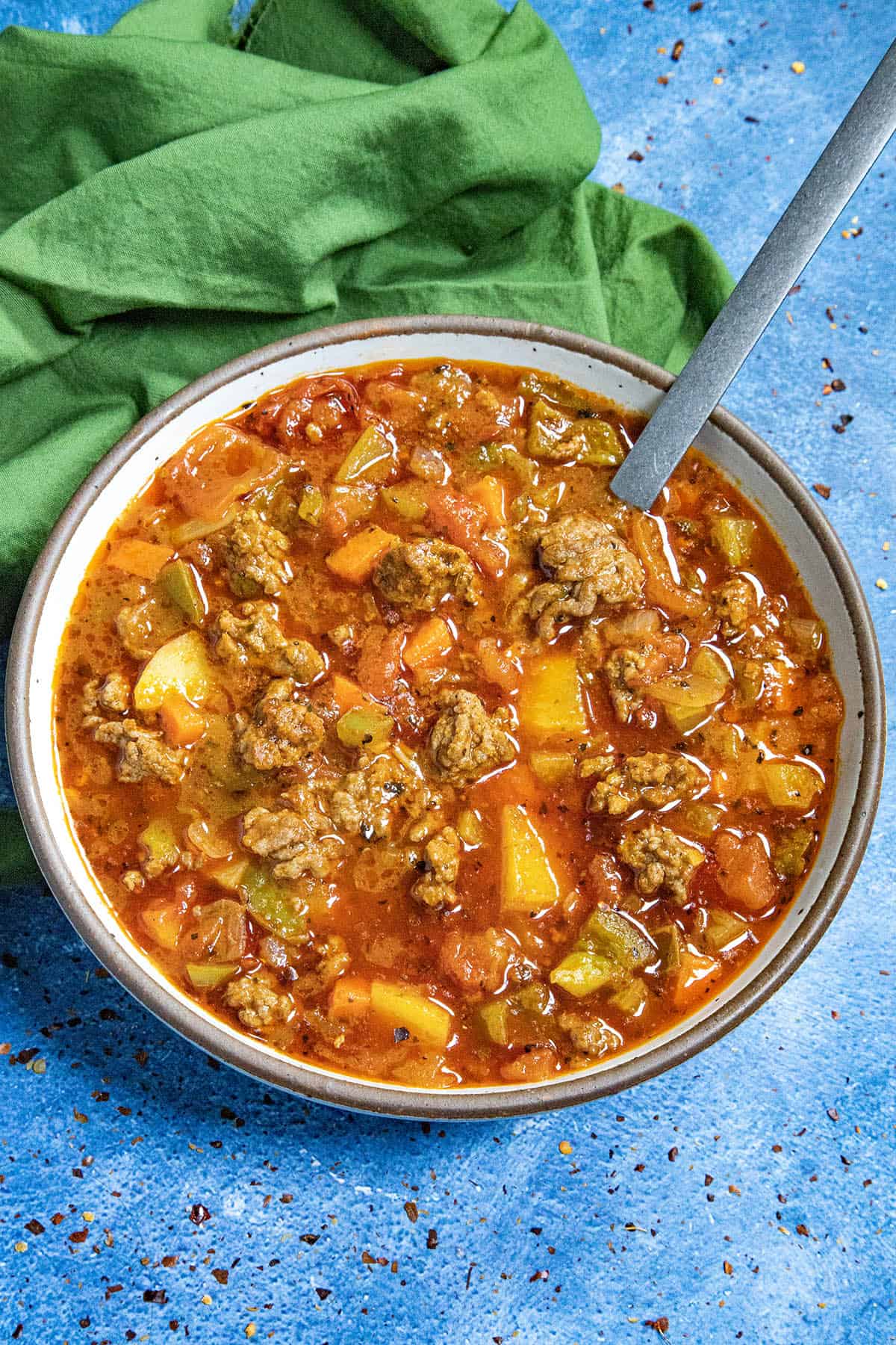 Chunky hamburger soup served in a bowl with a spoon, loaded with potatoes and seasoned ground beef