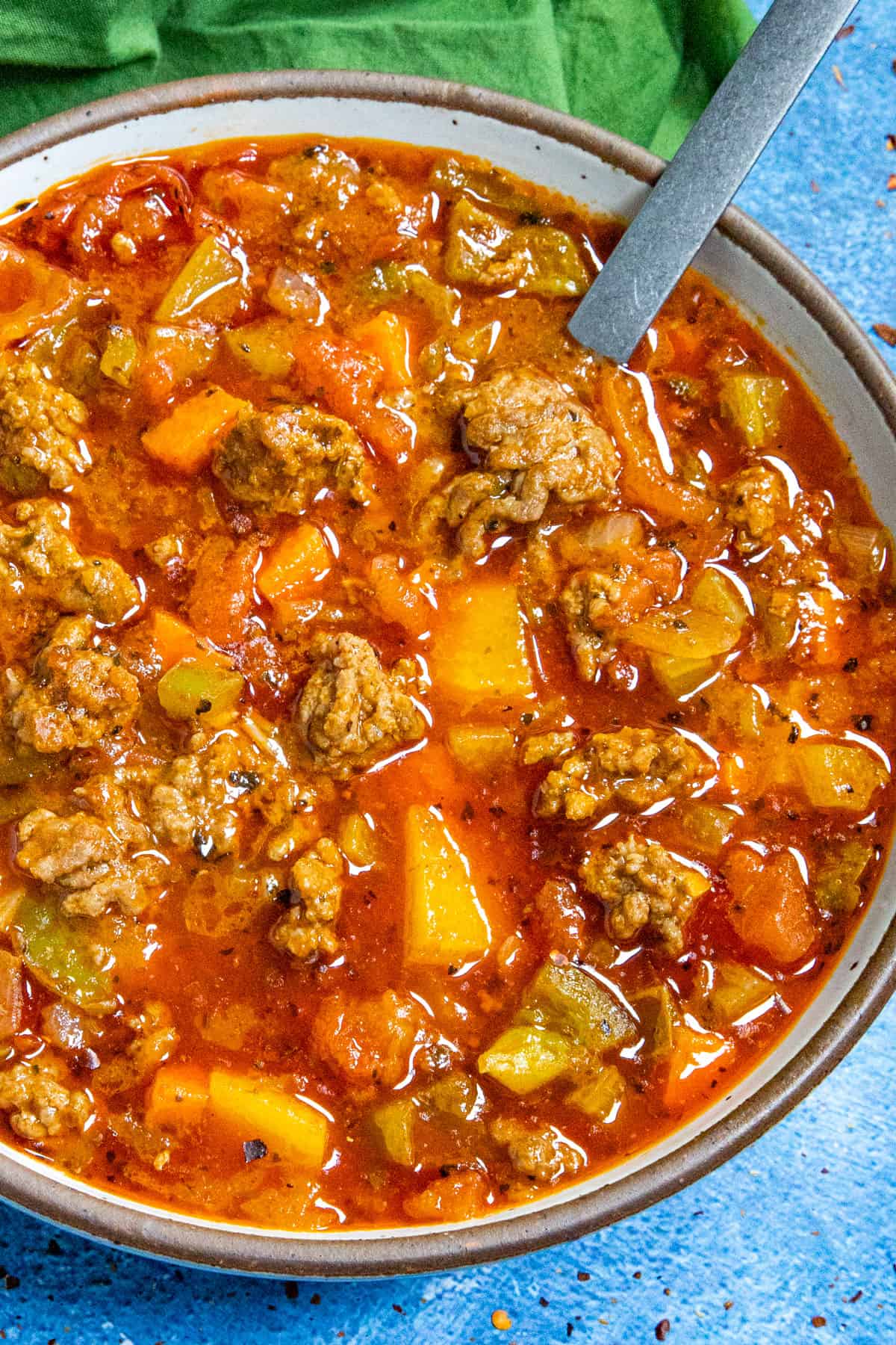 A bowl filled with chunky and brothy hamburger soup, with lots of ground beef and potatoes