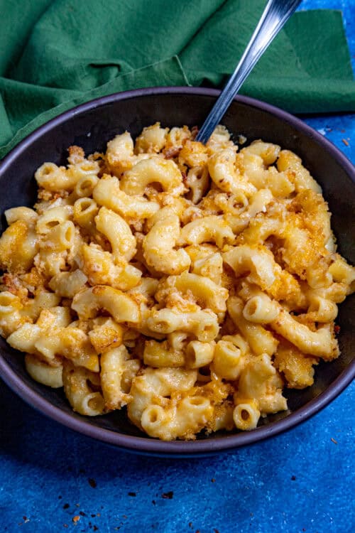 A large bowl filled with Creamy Mac and Cheese with extra cheese, served with a fork