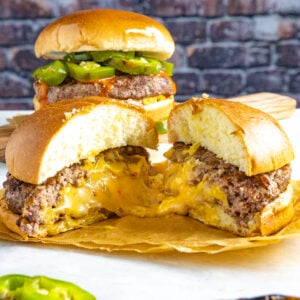 A gooey, cheese stuffed juicy lucy burger sliced in half, dripping with melty cheese