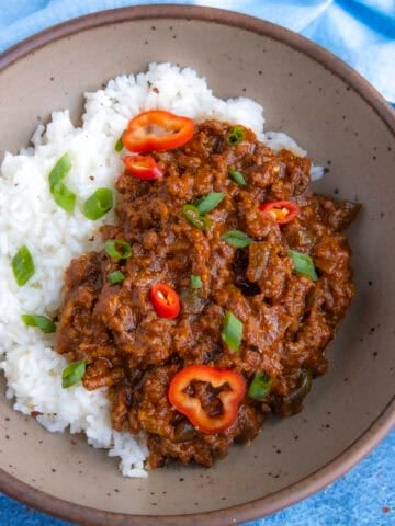 A Korean-Style Ground Beef bowl, made with tangy gochujang, served over rice in a bowl, topped with fresh sliced green onion and chilies