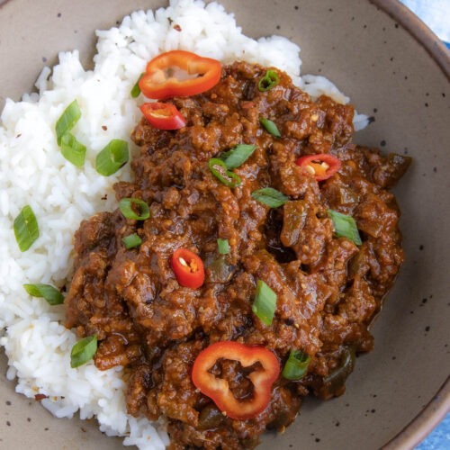 A Korean-Style Ground Beef bowl, made with tangy gochujang, served over rice in a bowl, topped with fresh sliced green onion and chilies
