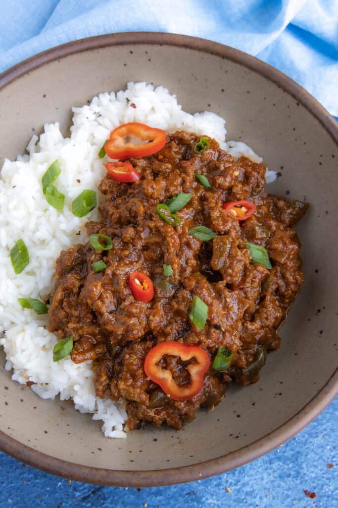 A Korean-Style Ground Beef bowl, made with tangy gochujang, served over rice in a bowl, topped with fresh sliced green onion and chilies