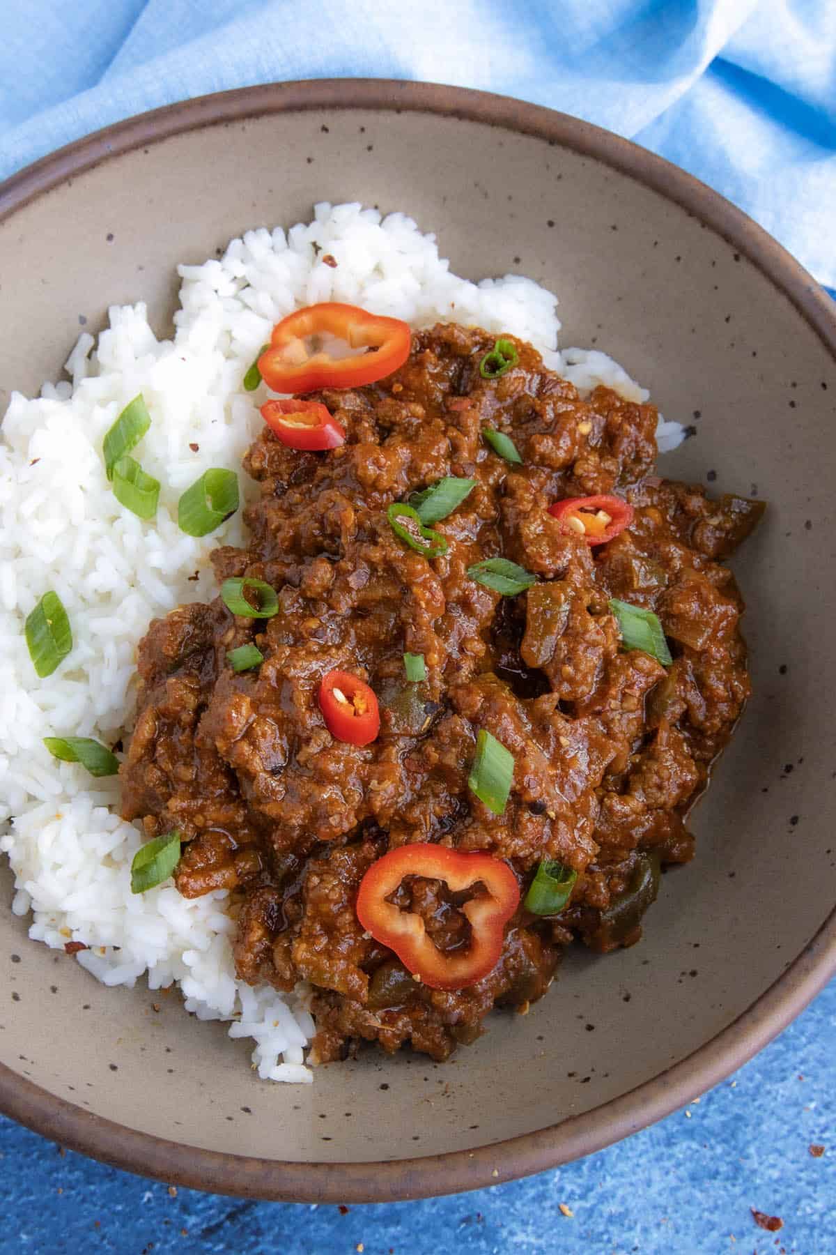 A Korean-Style Ground Beef bowl, made with tangy gochujang, served over rice in a bowl, topped with fresh sliced green onion and chilies