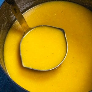 Creamy roasted garlic gravy being served from the pot with a ladle