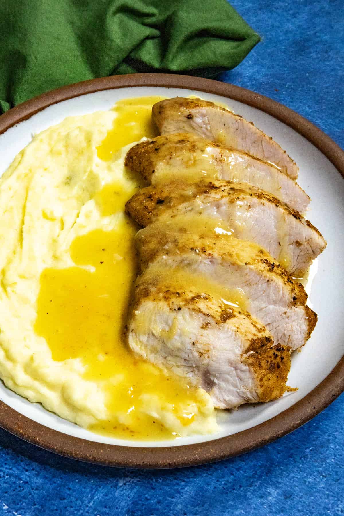 A plate filled with creamy mashed potatoes and sliced turkey breast, topped with rich roasted garlic gravy