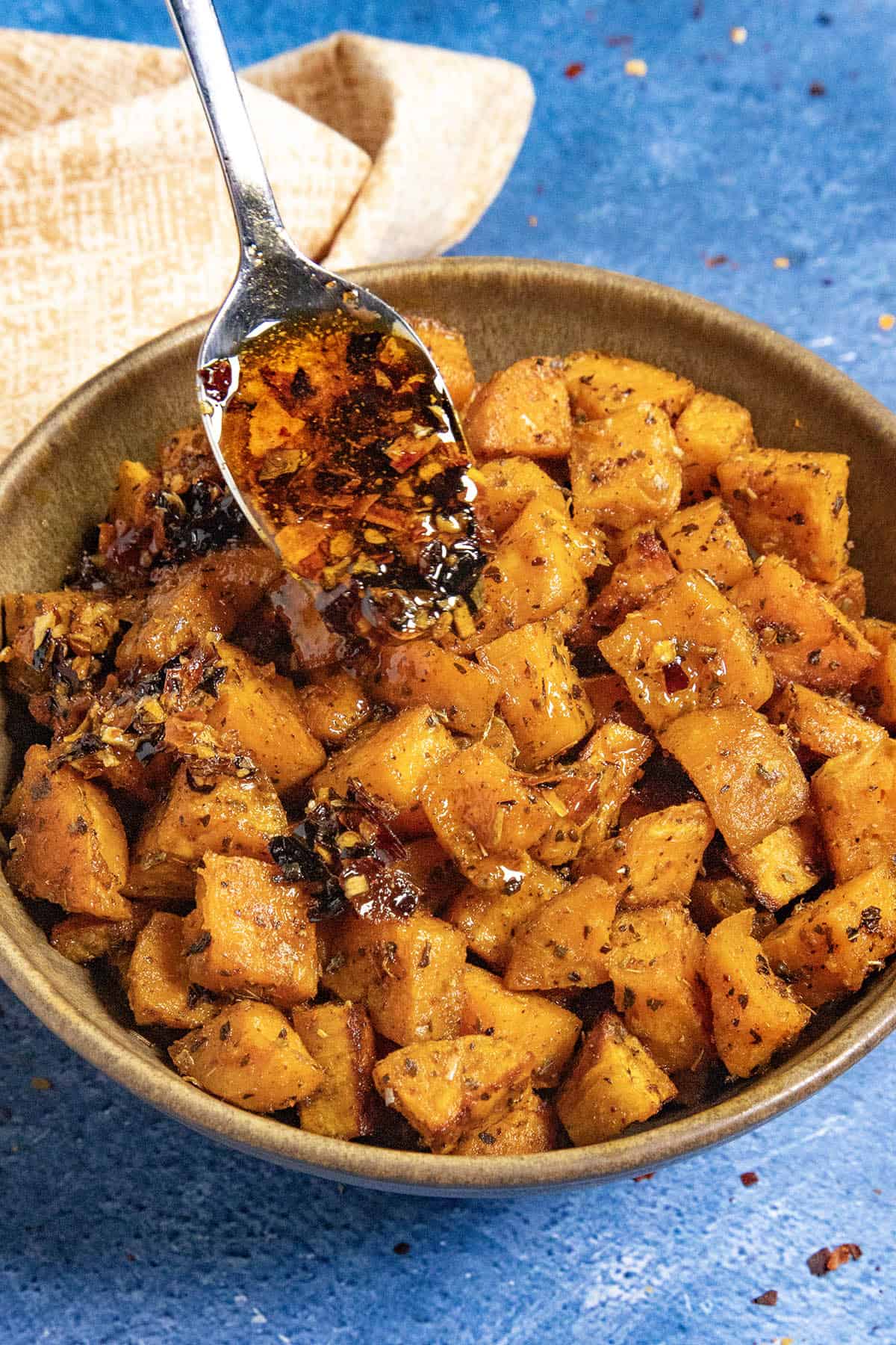 Mike drizzling chili crisp over a bowl of Roasted Sweet Potatoes