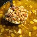 A spoonful of soup beans being served from the pot