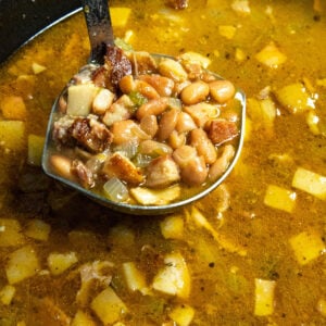 A spoonful of soup beans being served from the pot