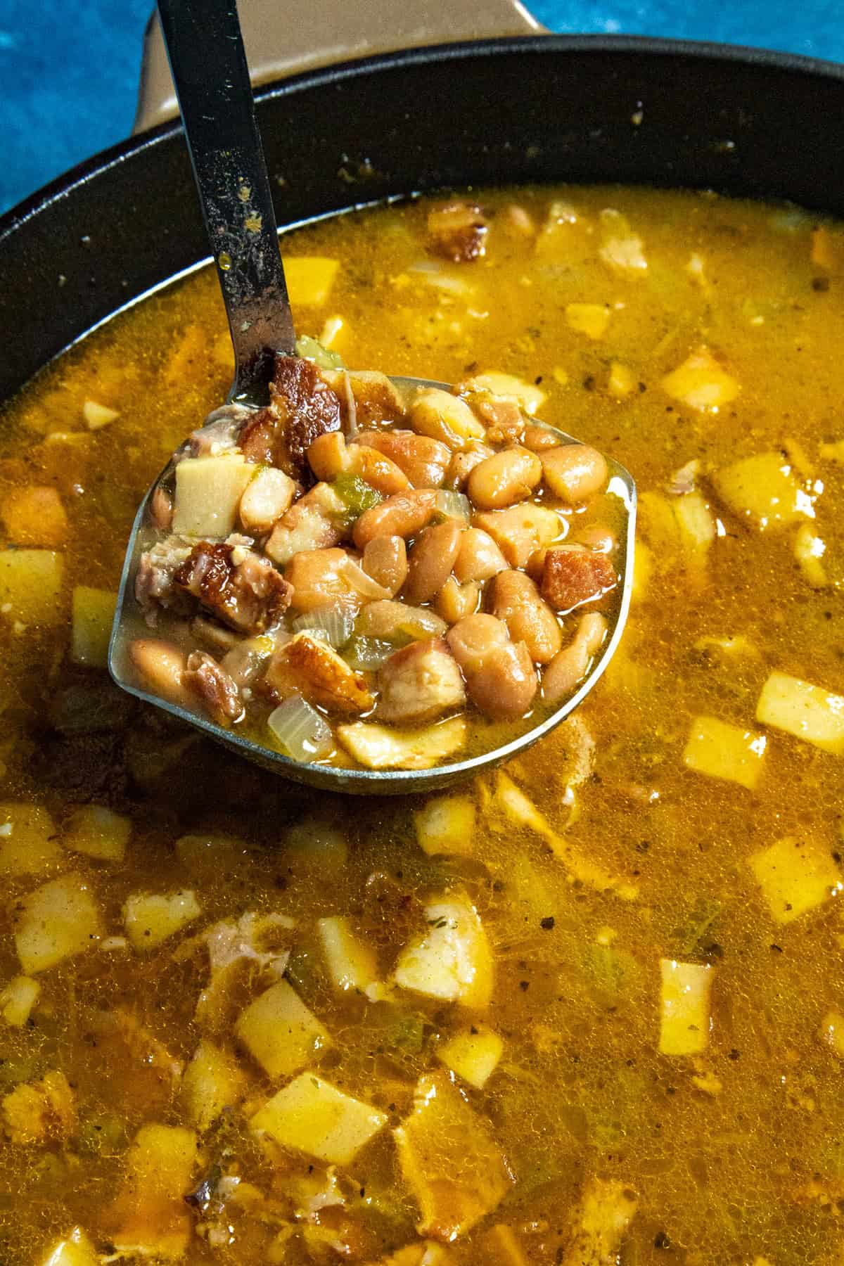 A ladle full of soup beans being served from the pot