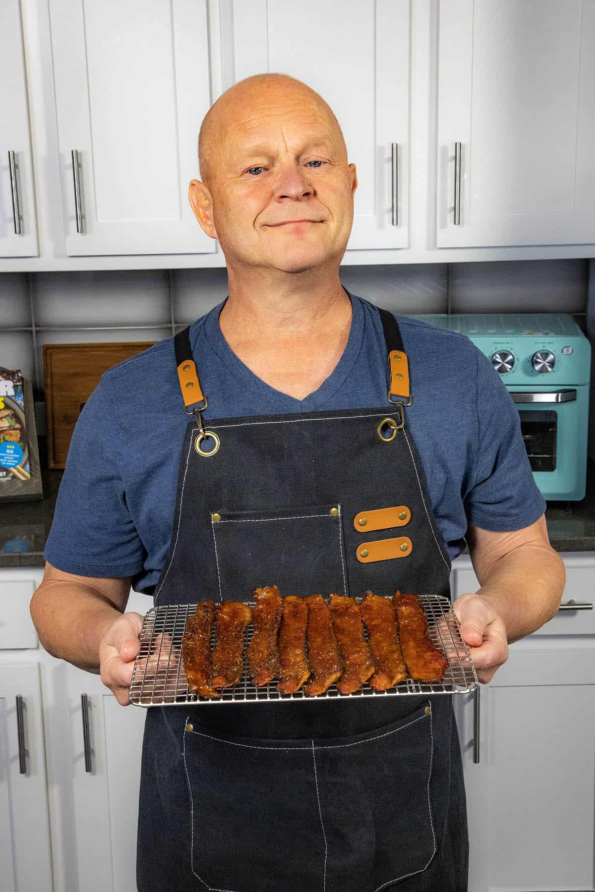 Mike from Chili Pepper Madness holding up a tray loaded with freshly made candied bacon, ready to serve