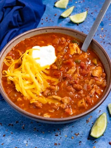 Homemade Chicken Chili in a bowl, topped with shredded cheddar cheese and sour cream