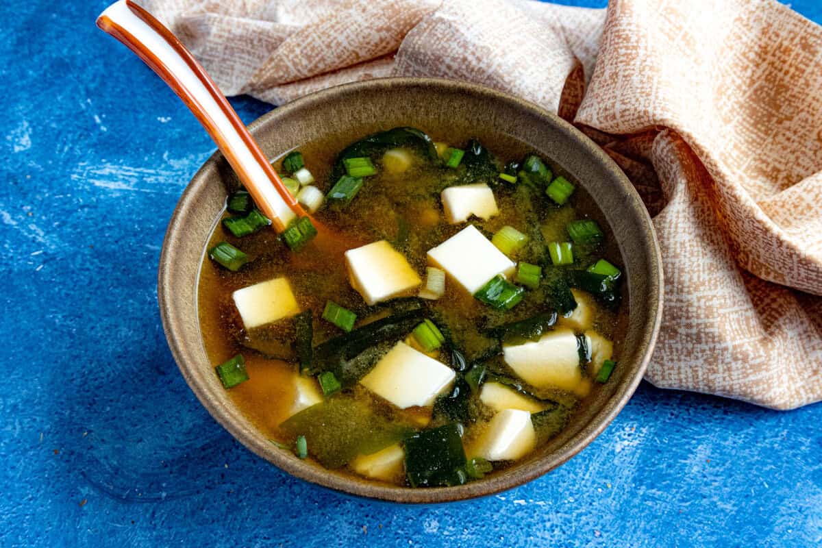 A bowl filled with homemade miso soup, filled with lots of cubed tofu and green onions