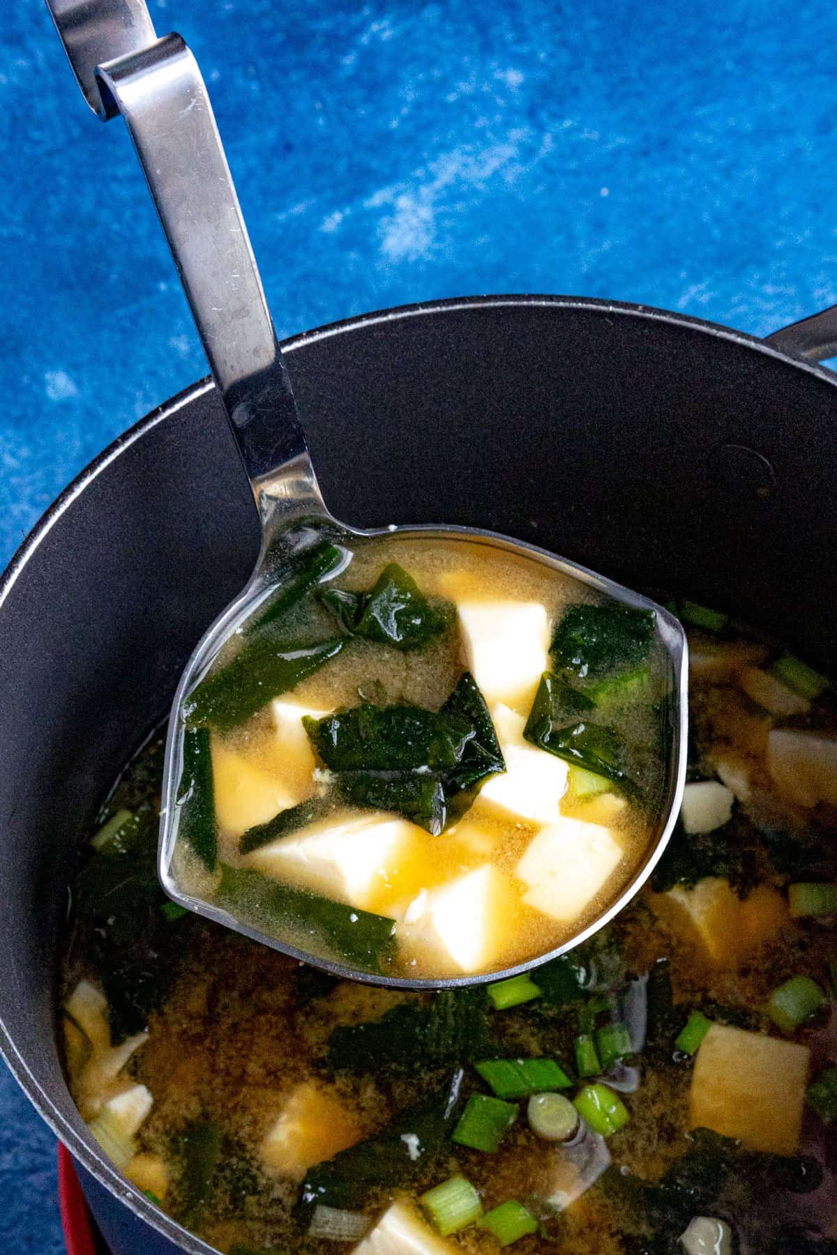 A ladle full of homemade miso soup being served from the pot