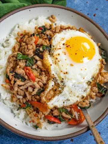 Thai holy basil stir fry (Pad Kra Pa) served in a bowl over rice, topped with a crispy fried egg
