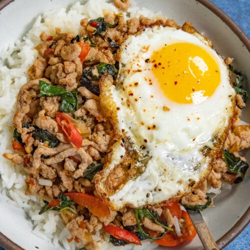 Thai holy basil stir fry (Pad Kra Pa) served in a bowl over rice, topped with a crispy fried egg