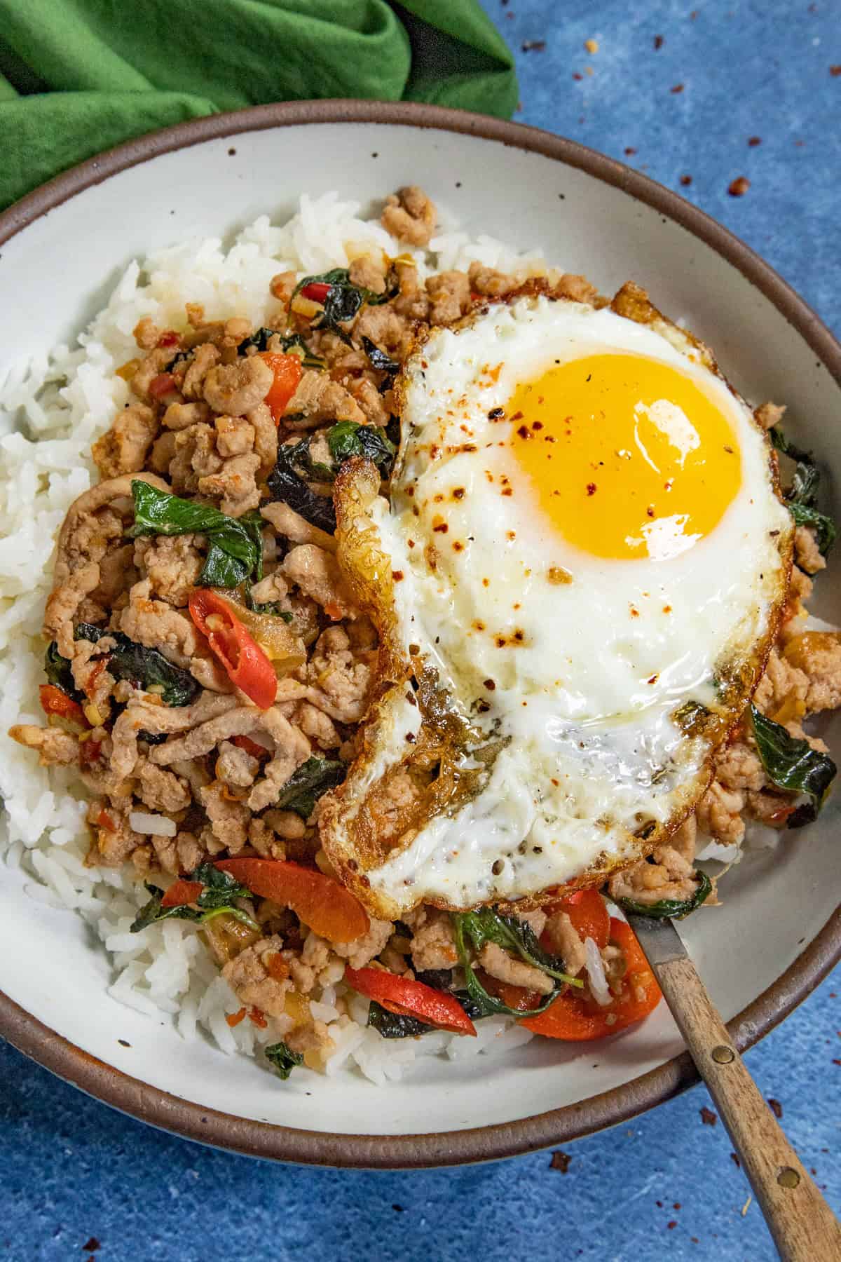 Thai holy basil stir fry (Pad Kra Pa) served in a bowl over rice, topped with a crispy fried egg