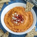 A bowl of Greek Whipped Feta Dip with Roasted Red Peppers (Htipiti) garnished with chopped peppers and feta