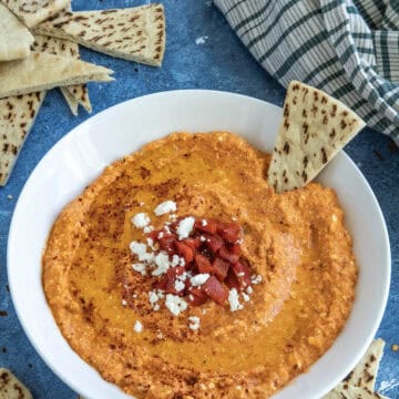 A white bowl filled with creamy Greek Whipped Feta Dip with Roasted Red Peppers (Htipiti)
