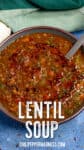 A bowl of Lentil Soup topped with red chili oil and herbs sits invitingly, a spoon resting inside.
