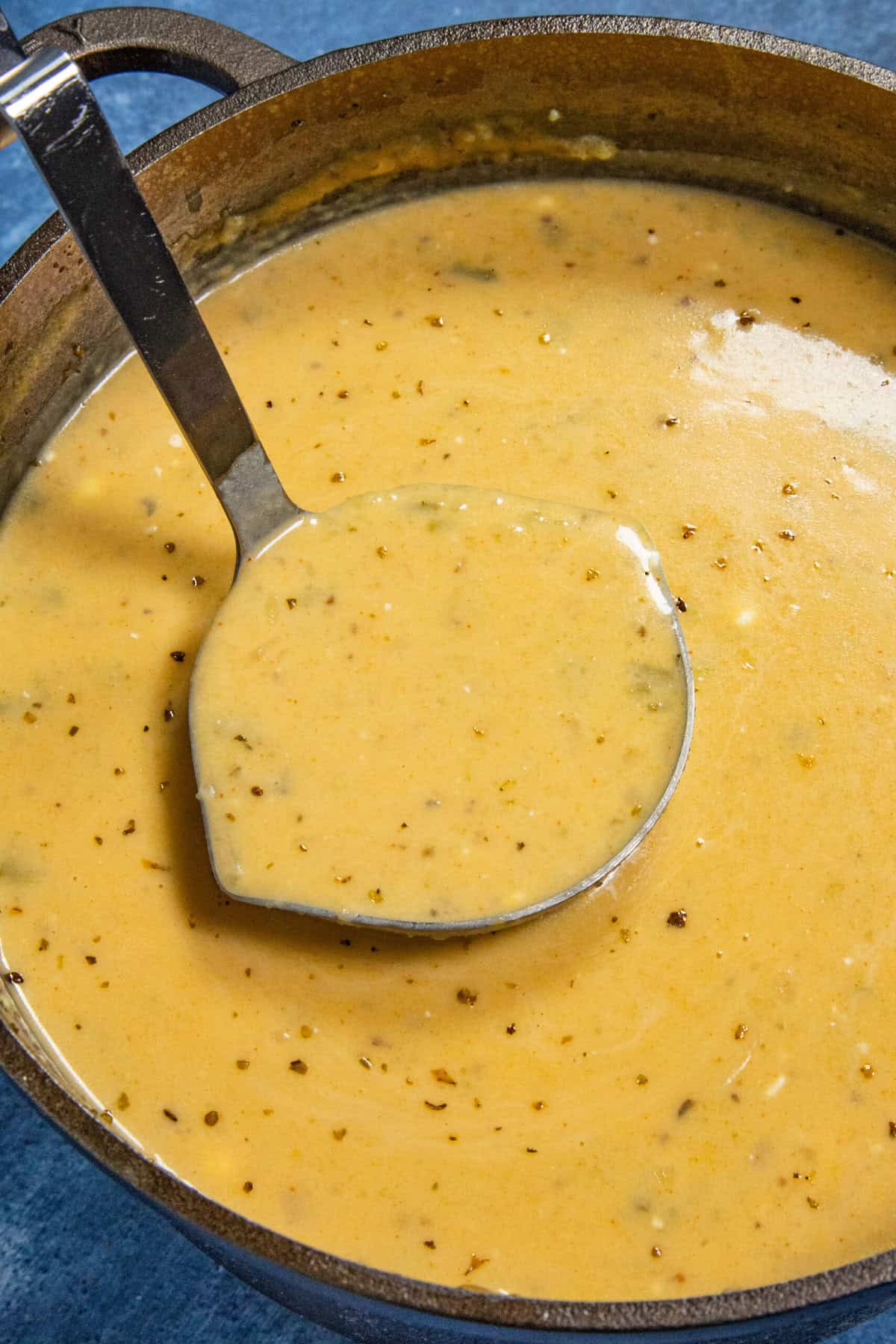Serving a scoop of creamy loaded baked potato soup from the simmering pot