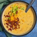 Loaded baked potato soup served in a bowl, garnished with crumbled bacon, shredded cheddar cheese, and chives