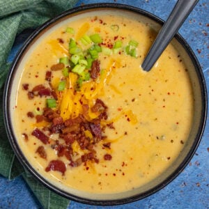 Loaded baked potato soup served in a bowl, garnished with crumbled bacon, shredded cheddar cheese, and chives