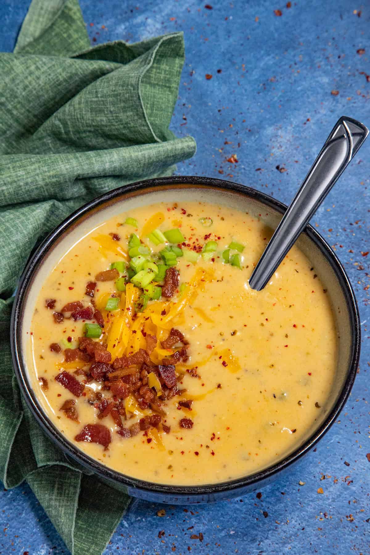 Baked potato soup in a bowl, garnished with crumbled bacon, chives, and shredded cheddar cheese, just like a loaded baked potato