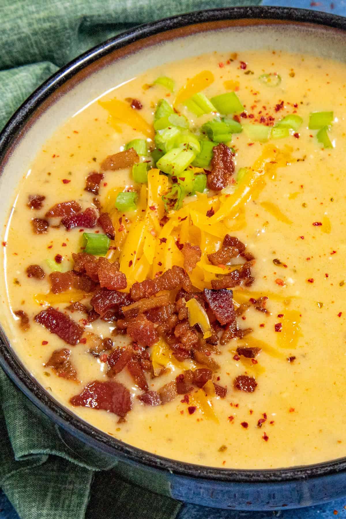 A large bowl of loaded baked potato soup garnished with crumbled bacon, shredded cheddar cheese, and chives