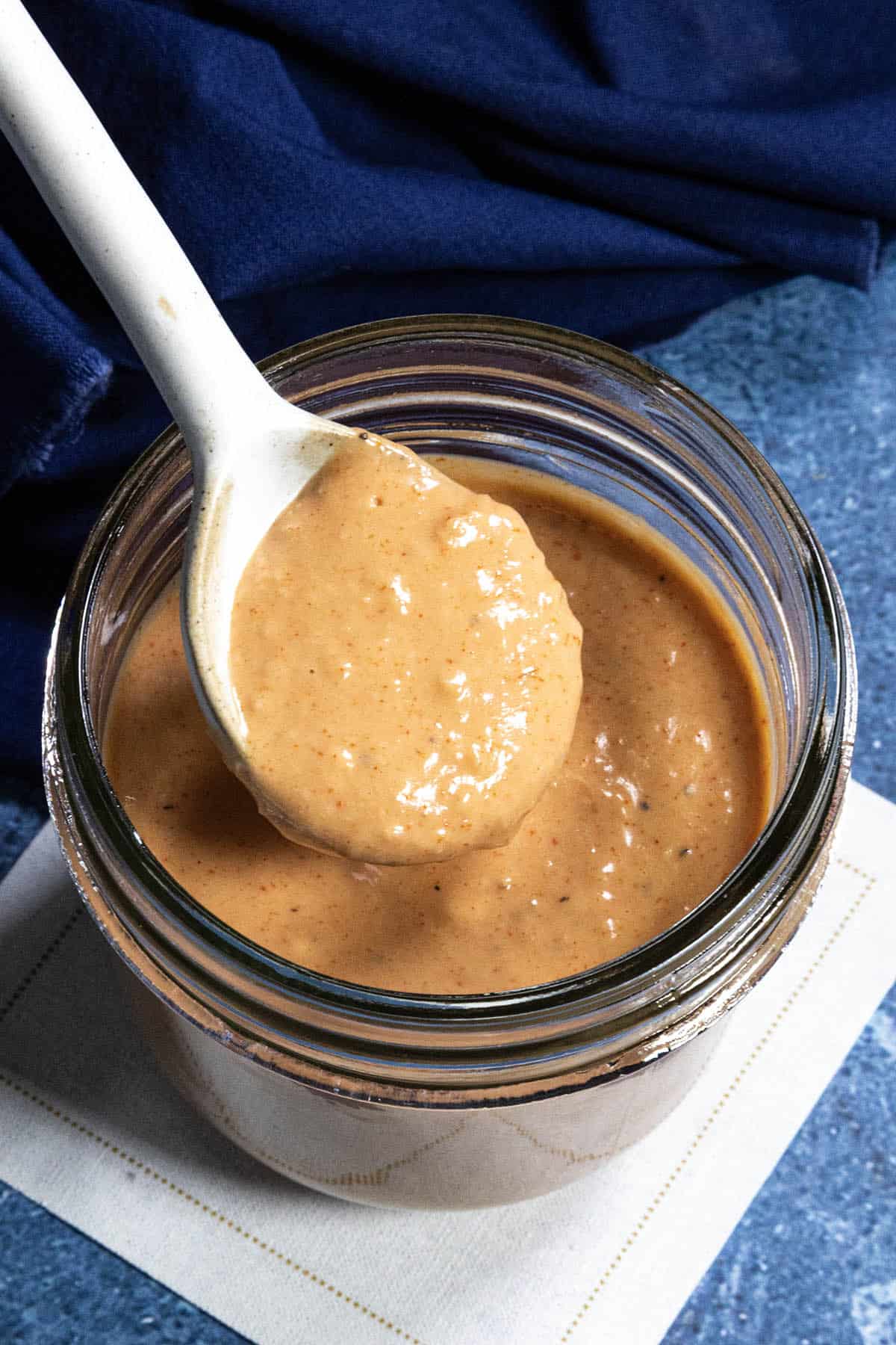 Creamy Russian Dressing dripping from a serving spoon into a glass jar
