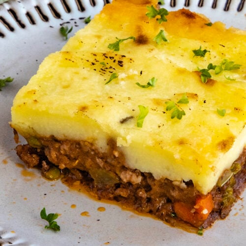 A generous serving of Shepherds Pie on a plate, garnished with fresh chopped herbs