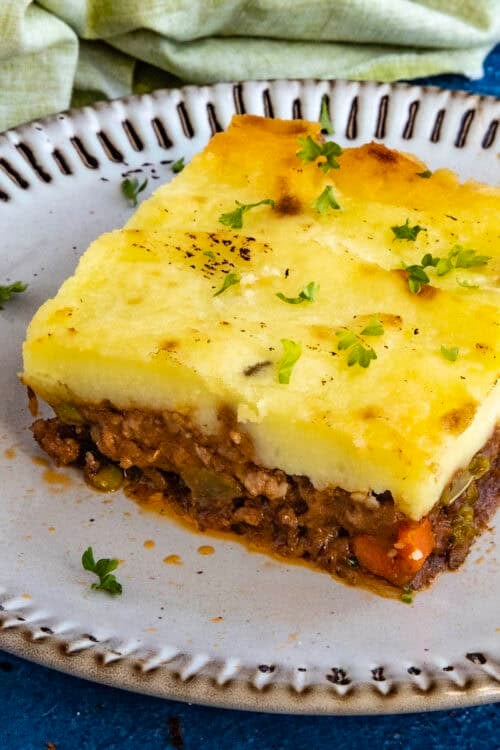A generous serving of Shepherds Pie on a plate, garnished with fresh chopped herbs