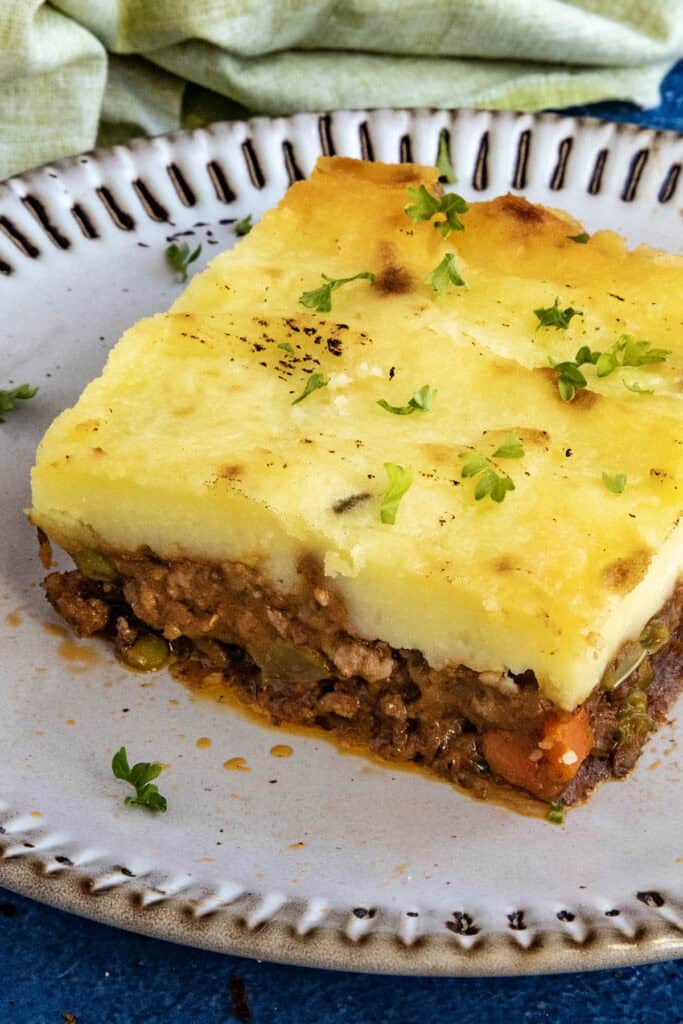 A generous serving of Shepherds Pie on a plate, garnished with fresh chopped herbs