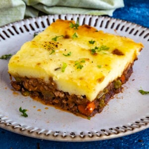 A generous serving of Shepherds Pie on a plate, garnished with fresh chopped herbs