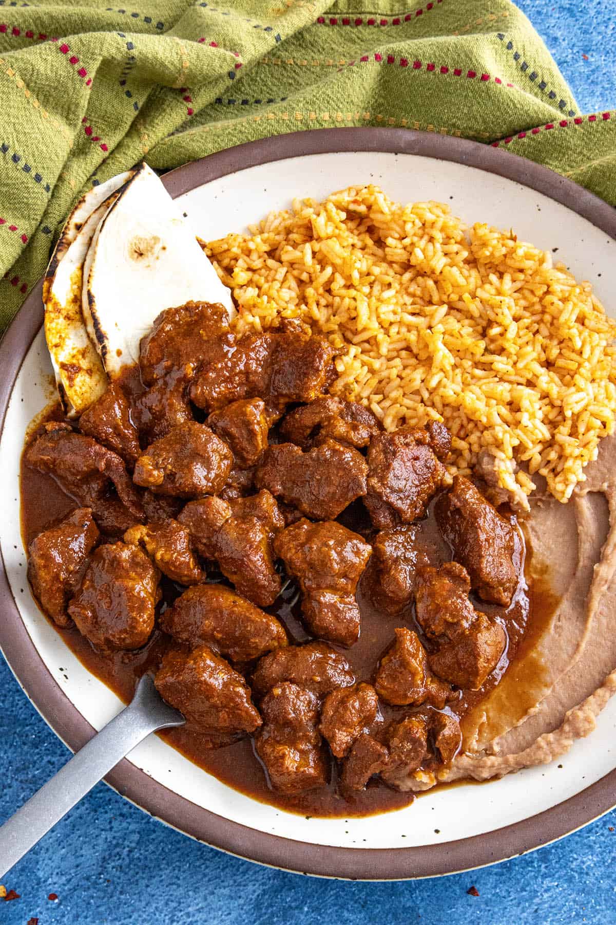 Asado de Puerco (Mexican Pork Stew) served on a plate with rice and refried beans