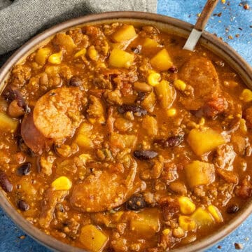 Chunky, meaty Cowboy Stew served in a bowl, loaded with andouille sausage, potatoes, beans and more
