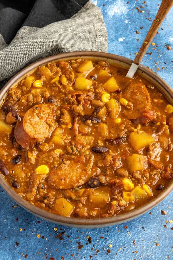Chunky, meaty Cowboy Stew served in a bowl, loaded with andouille sausage, potatoes, beans and more