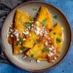 3 corn entomatadas served on a plate, stuffed with cheese, topped with mild tomato sauce