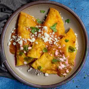 3 corn entomatadas served on a plate, stuffed with cheese, topped with mild tomato sauce