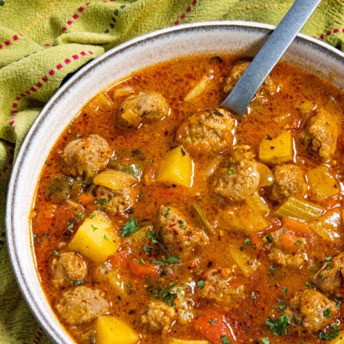 A large bowl filled with chunky Italian Sausage and Potato Soup, garnished with fresh parsley