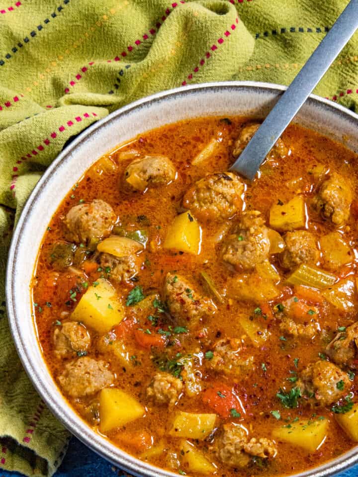 A large bowl filled with chunky Italian Sausage and Potato Soup, garnished with fresh parsley