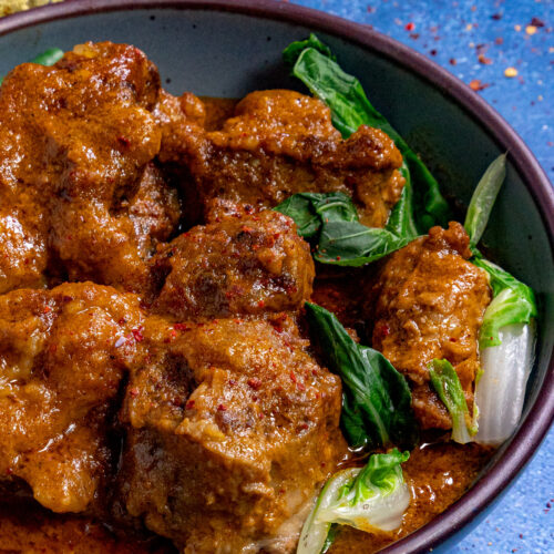 A bowl filled with Kare Kare (Filipino Beef Stew in Peanut Sauce)