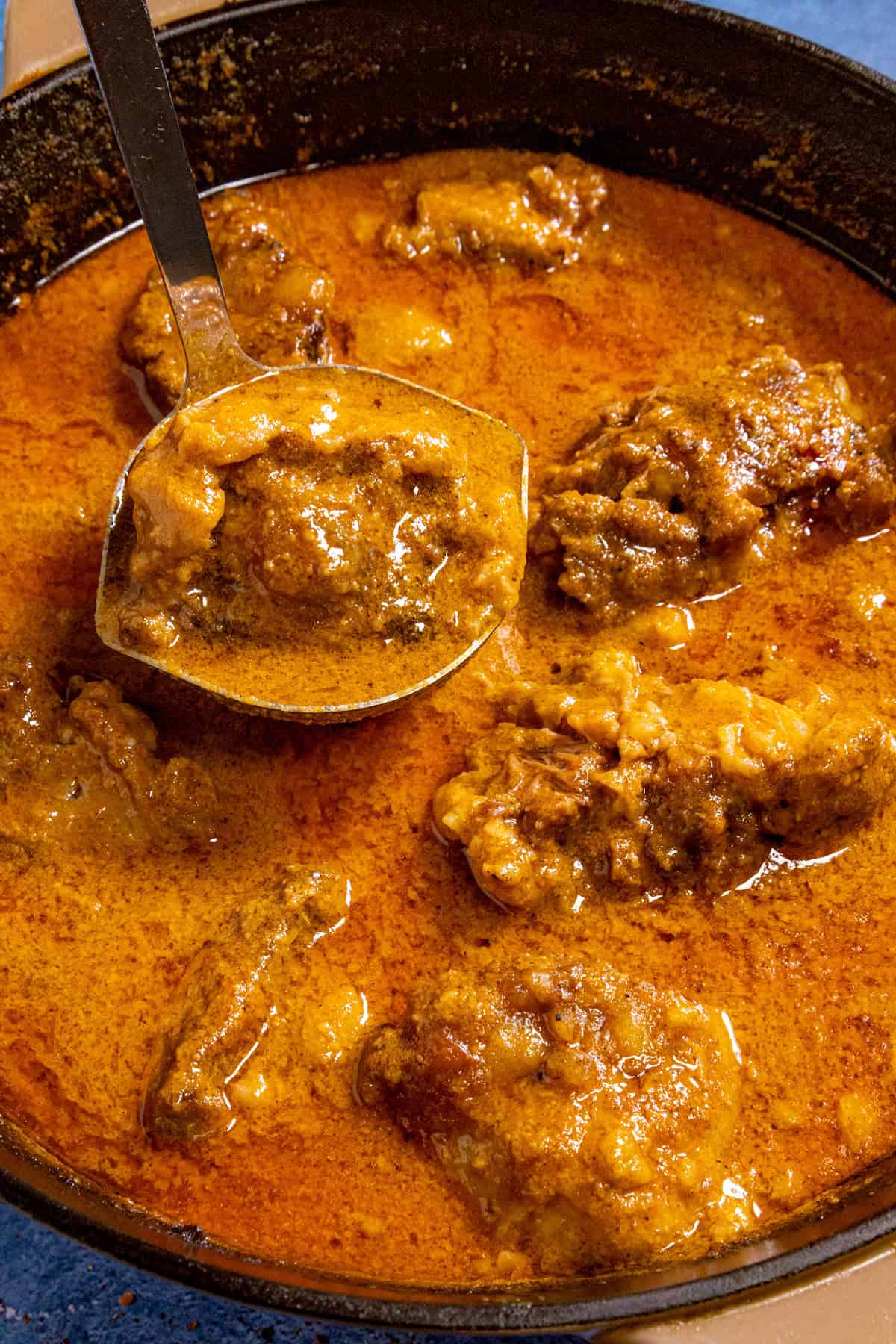 Serving a large scoop of kare kare stew from the pot with a spoon